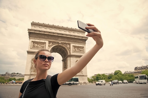 Young woman making selfie in front of Triumphal arch