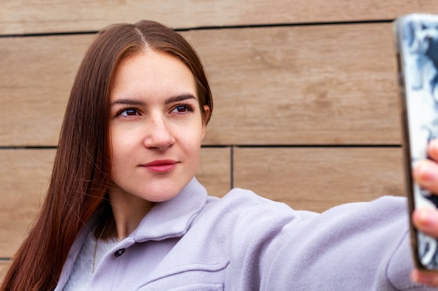 写真 携帯電話で自分撮りを作る若い女性