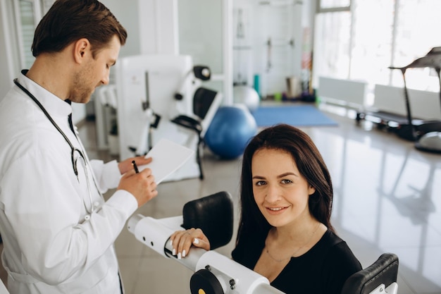 Young woman making spine examination in diagnostics machine with physiotherapist