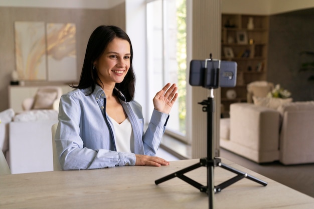 Foto giovane donna che fa un vlog a casa con il suo telefono