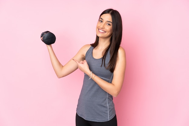 Young woman making weightlifting isolated on pink