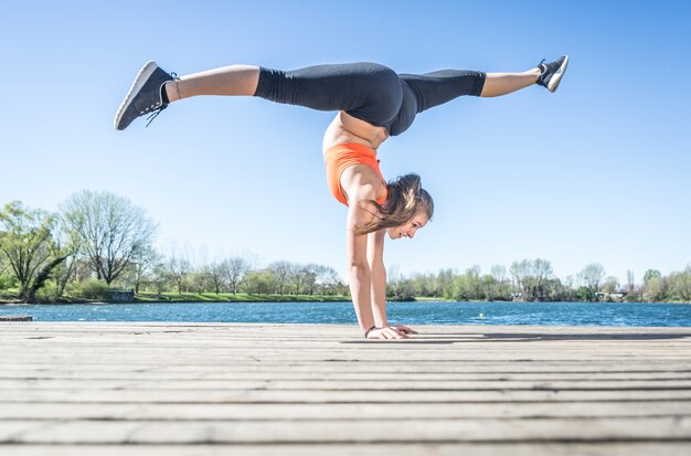 Young woman making yoga position  near the lake