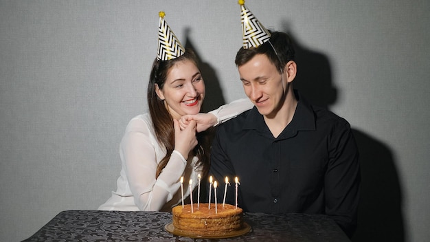 Young woman and man celebrates a holiday with a cake and a candles.