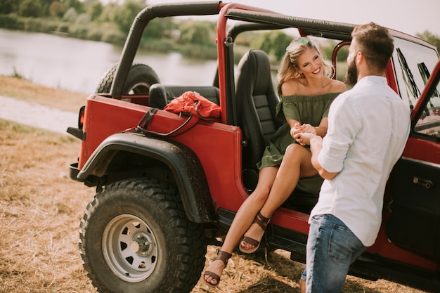 Young woman and man having fun outdoor near car