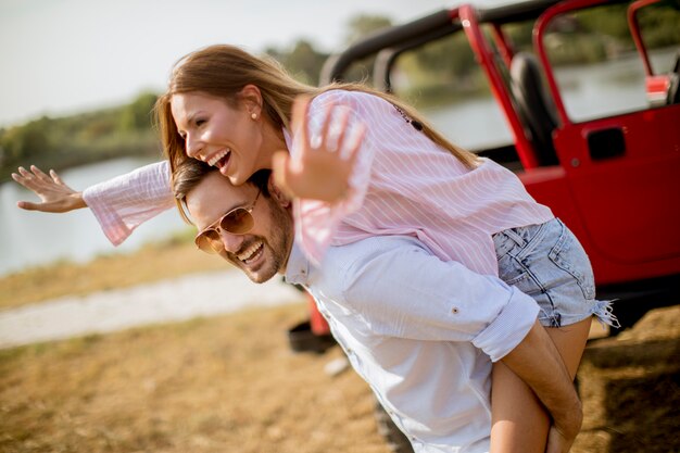 Young woman and man having fun outdoor near car