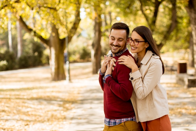 Young woman and man walking in city park holding hands