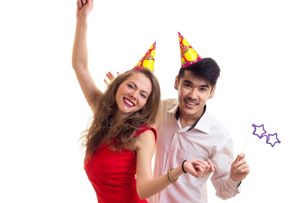 Young woman and man with celebrating hats holding many colored balloons and card sticks of glasses