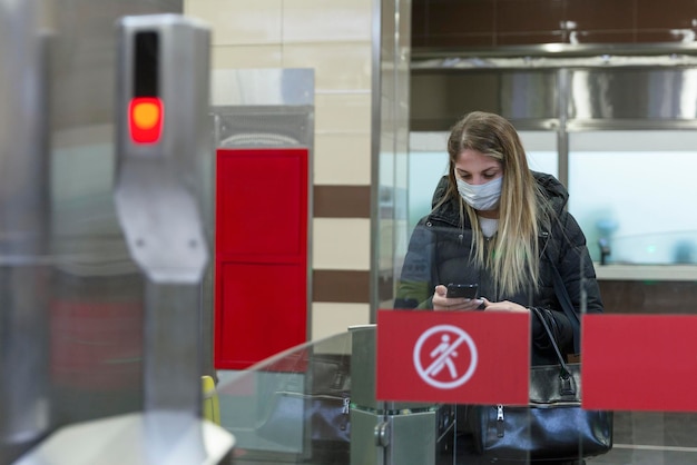 Foto una giovane donna in maschera entra nella metropolitana attraverso il tornello. pandemia di coronavirus e sicurezza.