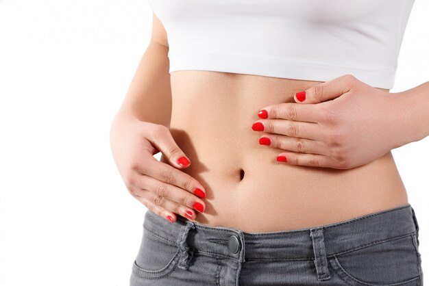 A young woman massages her stomach with two hands.