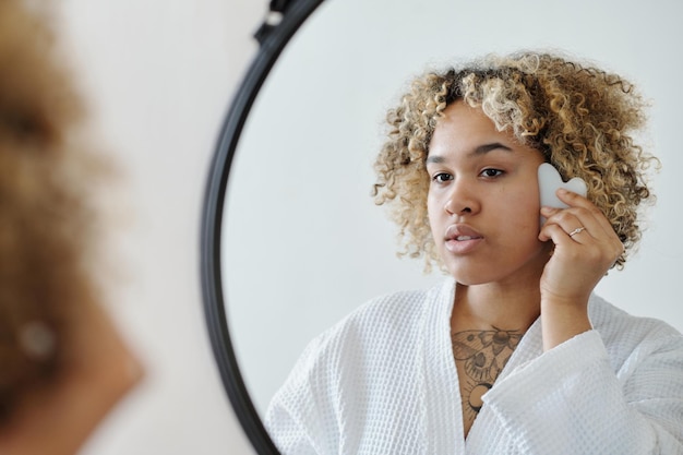 Young woman massaging her face with gua sha massager