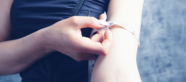 Young woman measures the girth of her arm