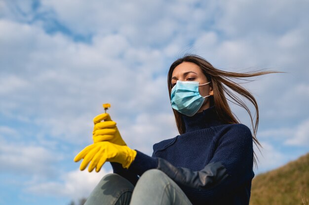 Foto la giovane donna in maschera medica e guanti seduta per terra