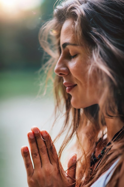 Photo young woman meditates practicing yoga in nature hands in prayer position