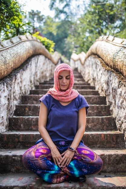 Young woman meditates in a temple in Laos, Asia