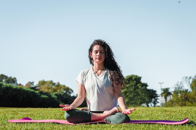 Premium Photo | Young woman meditating in lotus flower pose on a pink mat