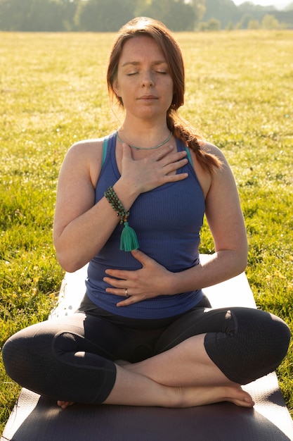 Foto giovane donna che medita all'aperto sul tappetino da yoga