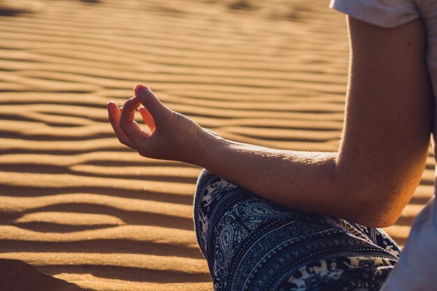 Foto giovane donna meditando nel deserto sabbioso rad al tramonto o all'alba