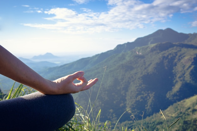 Photo young woman meditating on top of a mountain
