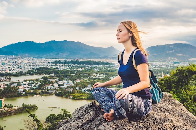 Young woman meditating on top of a mountain