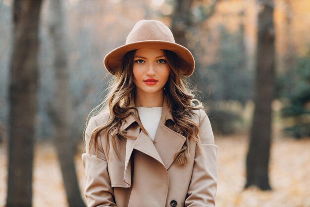 Young woman model in autumn park with yellow foliage maple leaves Fall season fashion