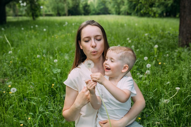 Young woman mom and son play in nature spend time together and have fun