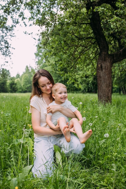 Young woman mom and son play in nature spend time together and have fun