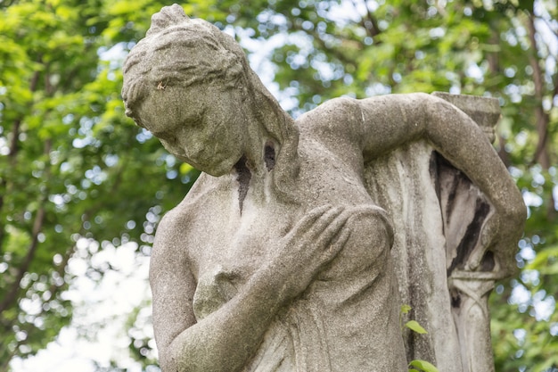 Young woman monument on a tomb at a graveyard