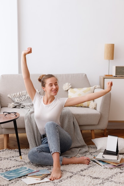 Young woman in the morning in the living room surrounded by books