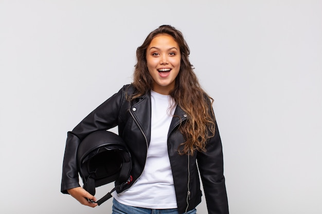Young woman motorbike rider looking very shocked or surprised, staring with open mouth saying wow