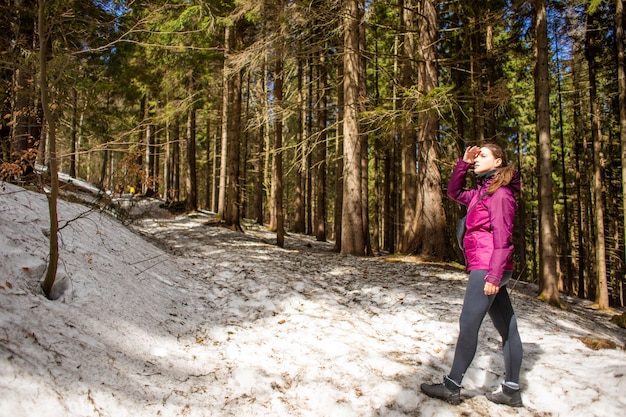 Young woman in mountain forest in sunny day watching forward