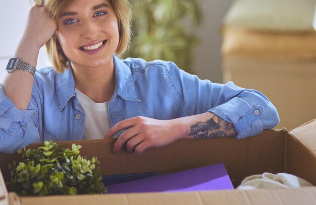 Young woman moving into new home sitting near box