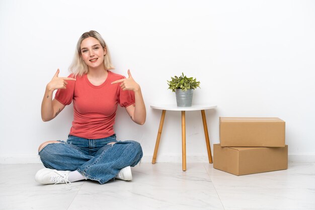 Young woman moving in new home among boxes isolated on white background proud and selfsatisfied