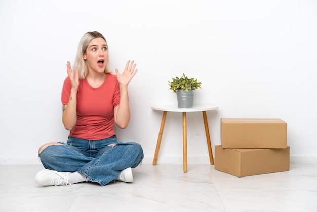 Young woman moving in new home among boxes isolated on white background with surprise facial expression