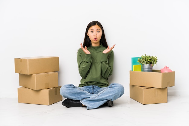 Young woman moving to a new home surprised and shocked