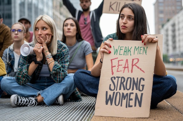 Foto giovane donna in un gruppo multirazziale di persone in sciopero per l'uguaglianza e attivisti per i diritti delle donne in protesta in città