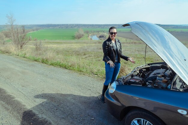 助けを求める車の近くの若い女性