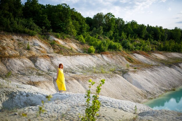 紺碧の水と緑の木々と石の山々と湖の近くの若い女性。森の中の湖の美しい景色
