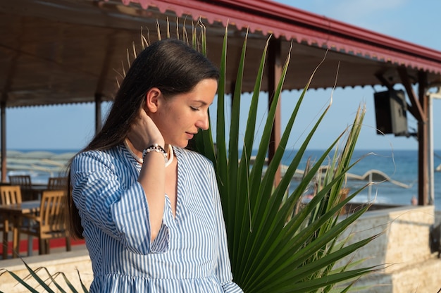 Young woman near palm leaf.