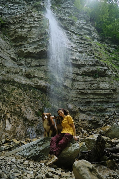 Young woman near waterfall with two dogs Front view Wanderlust travel pets concept