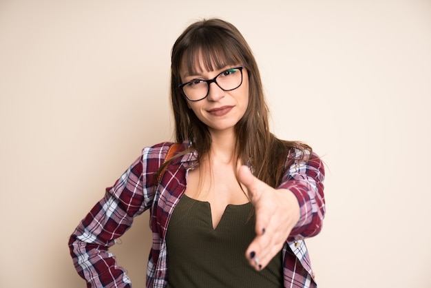 Young woman on ocher background handshaking after good deal