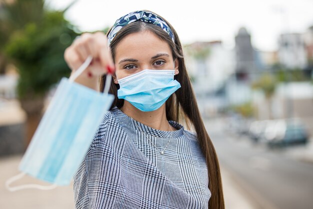 ウイルスの流行に対する保護マスクを提供する若い女性