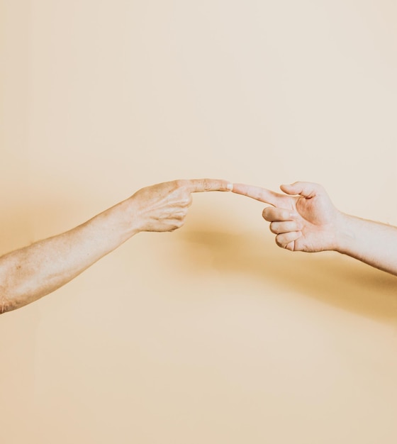 Young woman and old woman touching fingers on yellow background.Minimalism fashion. Surrealism. Concept art Senior and young holding hands