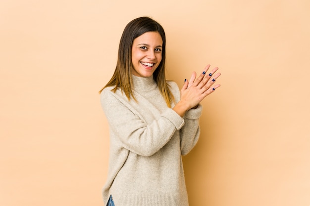 Фото Молодая женщина на бежевой стене чувствует себя энергичной и комфортной, уверенно потирает руки.