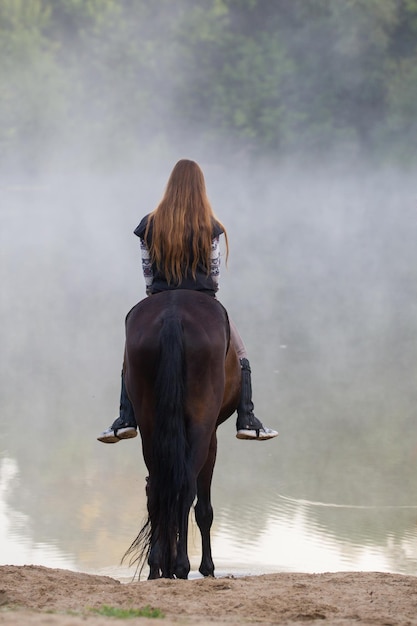 写真 湖に行こうとしている馬の若い女性早朝の霧
