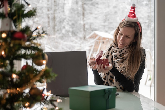 Young woman opening a christmas gift while on video call