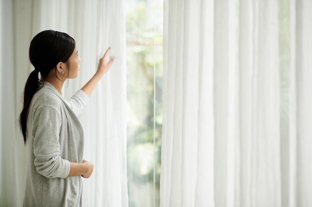 Young Woman Opening Curtains