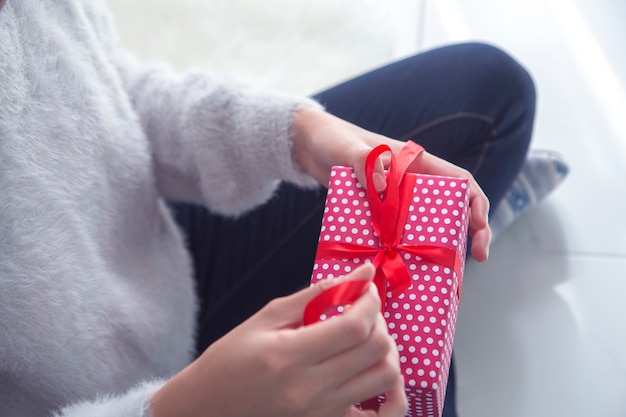 молодая женщина, открытие подарочной коробке с красной лентой.