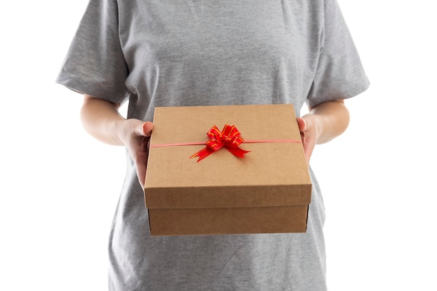 Young woman opening Valentine's Day gift on white room