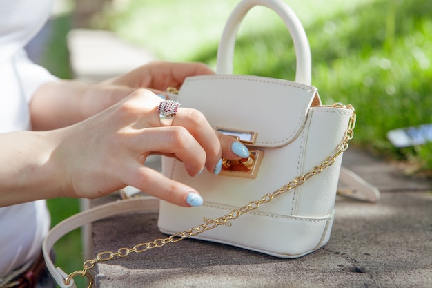 Young woman opens her bag in the park