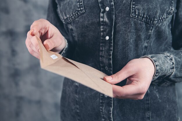 Young woman opens a mail envelope